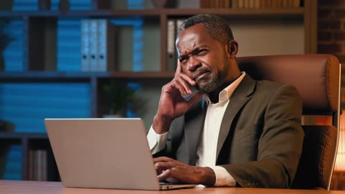 Pensive Puzzled Man Sitting in Office Working on Laptop Think Ponder Strategy Pondering Difficult