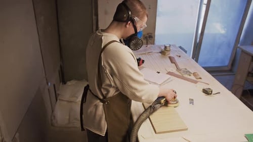 Young Woman Polishing Wooden Board with Electric Sander in Carpentry Workshop