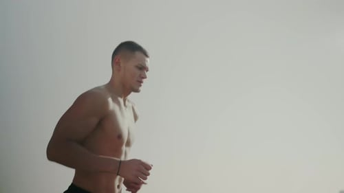 Morning Jog Along the Beach Captures Shirtless Male Runner