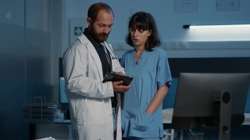 Doctor and Nurse Discussing Tablet in Hospital