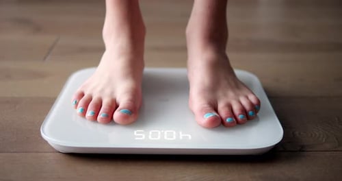 Person Weighing Themselves on Digital Bathroom Scale
