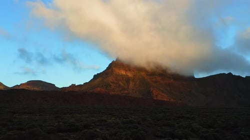 Sunset Rays Illuminating Hot Desert Mountain Landscape with Clouds Background in Teide National Park