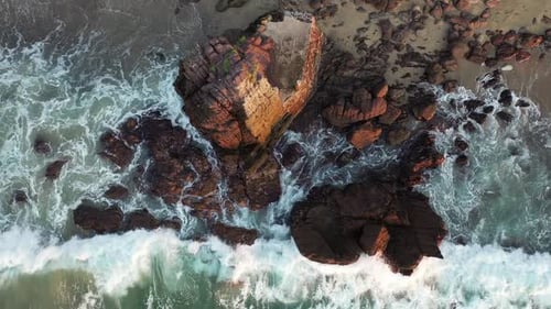 Aerial shot of waves rolling and crashing over rocks on a sandy beach. Puerto Vallarta, Jalisco, Mex