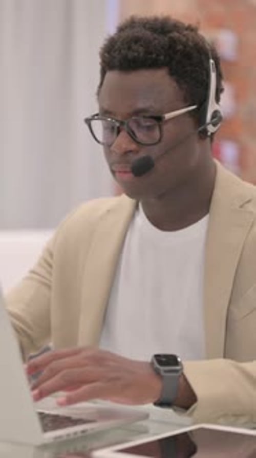 Young Adult Man Working at Computer Wearing Headset