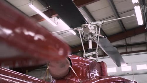 Slow motion panning view of helicopter top under construction in hangar