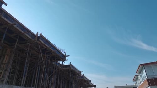 Grúa aérea de vídeo que opera en una obra de construcción con trabajadores trasladando metal y materiales a