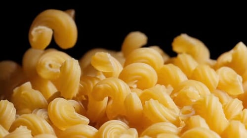 Raw macaroni pasta falls gracefully in stunning slow motion.