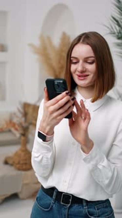 Pretty brunette girl uses her phone and smiles. Man sitting at backdrop is busy with his laptop.