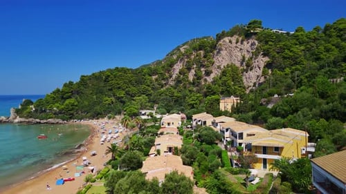 Aerial View of Beachside Villas and Green Mountains under Clear Blue Sky