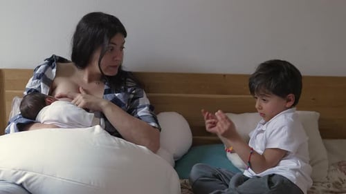 Mother breastfeeding her baby, engaging in a conversation with her older son. family's close bond,