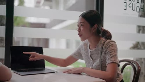 Women Collaborating with Laptop in Bright Office Space