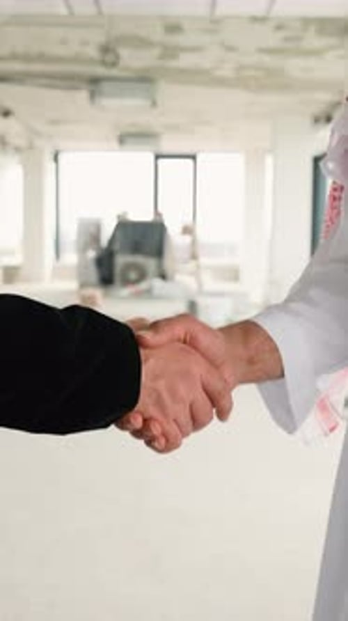 Empresarios dándose la mano en un edificio inacabado