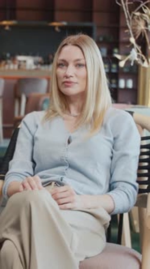 Portrait Attractive Blond Young Woman Using and Typing Laptop in a Cafe Sitting Looking at Camera