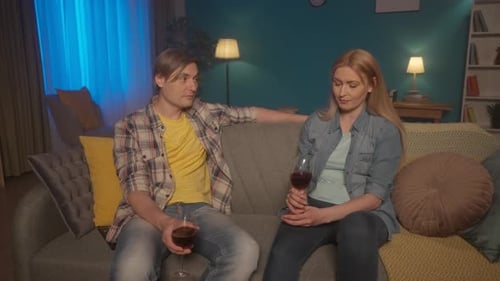 A Young Married Couple Sits on the Sofa in the Evening Talking Drinking Wine A Man Shares the Events