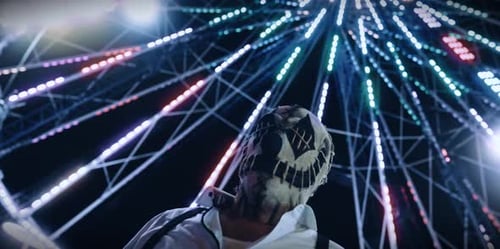 Masked Person Under Ferris Wheel at Night