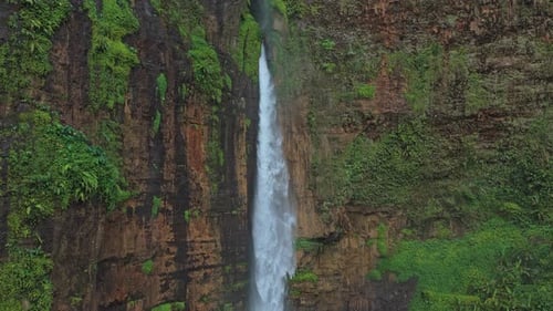 Scenic waterfall flowing down a green mossy canyon