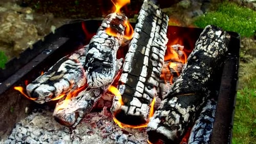 Close-up of flaming logs in metal grill