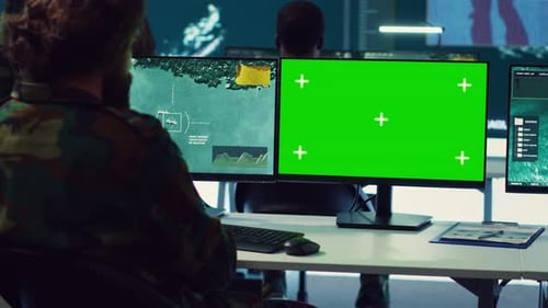 Two People Working at Desktop Computers With Green Screen