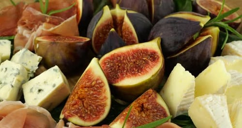 Figues, jamons, feuilles d'épinard et fromages bleus sur une planche de bois. Set de snacks.