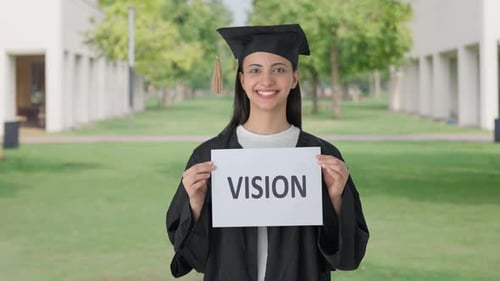 Happy Indian college graduate girl holding VISION banner