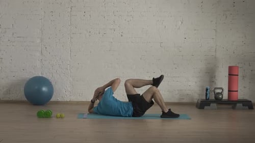 Männlicher Fitnesstrainer in Sportbekleidung macht Bauchmuskelübungen zum Umhängen für den Online-Kurs an der
