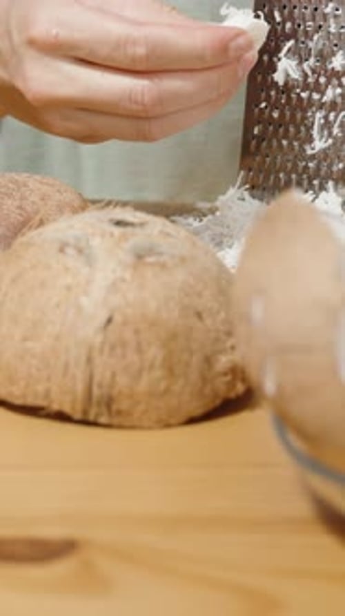 Vidéo verticale. Des morceaux de noix de coco et leur chair blanche sont étalés sur la table.