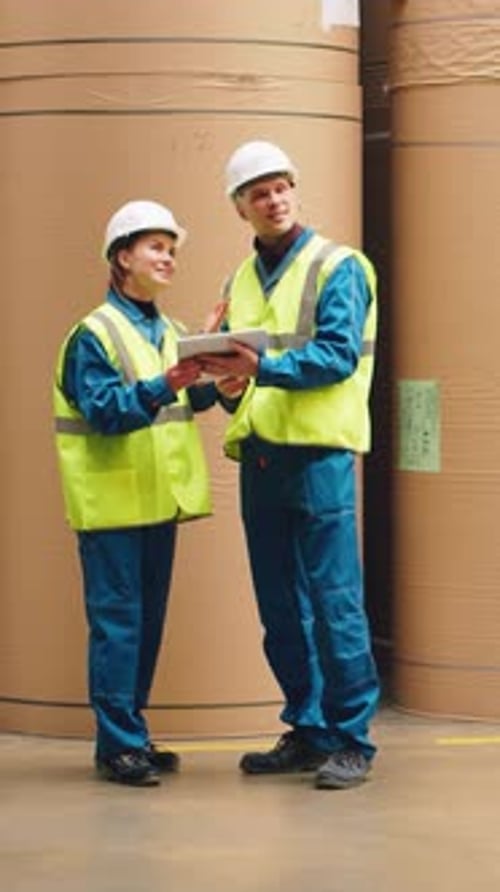 Paper Industry Engineers Inspecting Paper Rolls in a Warehouse and Talking Inventory of a Warehouse