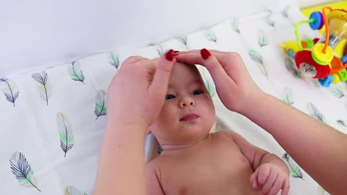 Mother Massaging Face of Baby at Home