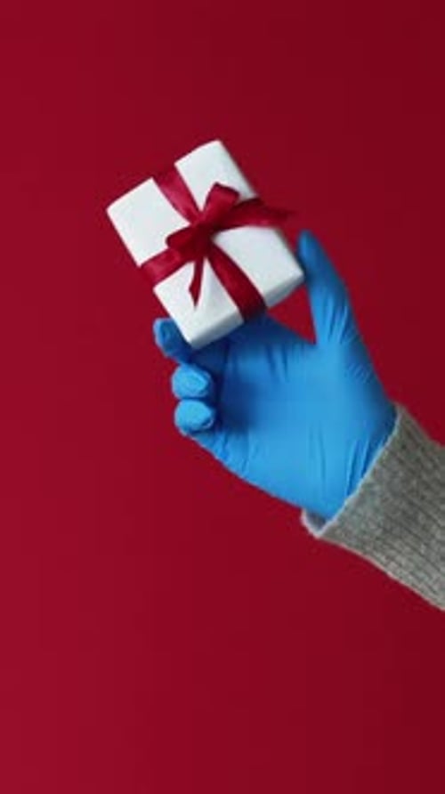 Gloved Hand Holding Gift with a Red Bow