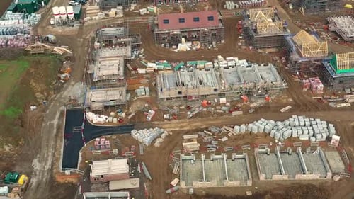 Construction, aerial sweeping shot of Red Digger moving block. New build site 60fps