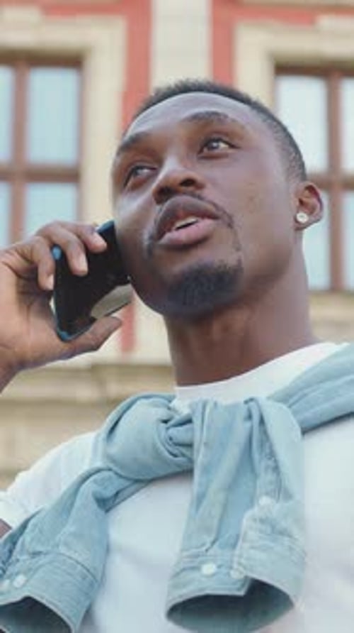 Handsome Positive Smiling Man Has Pleasant Phone Conversation Outdoors Near Ancient City