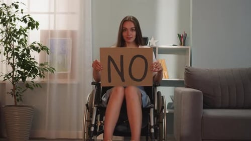 Young Woman in Wheelchair Holds a Sign That Says No