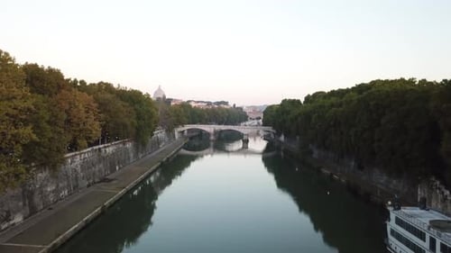 Drone flying above the river that runs through the city of Rome, Italy, with several houses in the b
