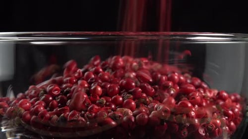 Red Peppercorns Being Poured into Glass Bowl