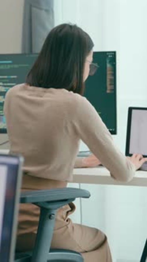 Woman Working at Desk with Multiple Computer Screens
