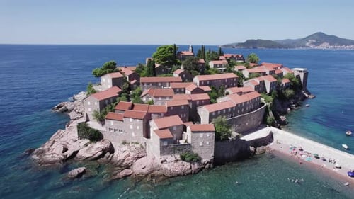 Eine Drohne fliegt an einem sonnigen Tag in Montenegro über die Insel Sveti Stefan
