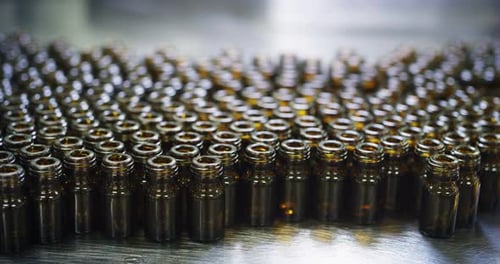 Gros plan de la production de médicaments dans des flacons de verrerie sur des lignes automatiques dans une usine pharmaceutique
