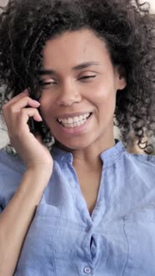 Smiling Woman Uses Mobile Phone for Call Indoors