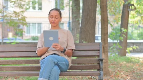 Woman Using Tablet Computer Sitting on Park Bench