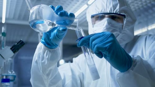 Lab Technician Pours Liquid Into Test Tube in Hazmat