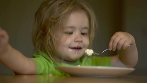 Happy Child Eating Meal at Table