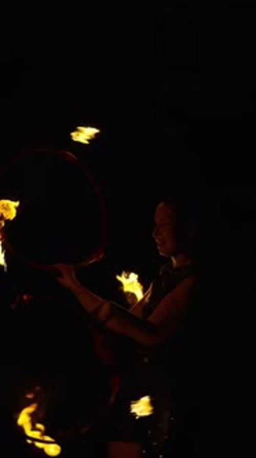 Dynamic Fire Dancer Performing with Flaming Props in the Darkness Creating Dramatic Light Trails and