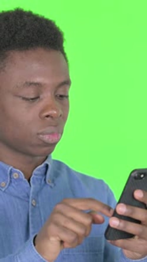Young African Man with Loss on Smartphone on Green Background, Vertical Video