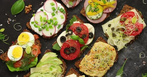 Verschiedene offene Sandwiches auf dunklem Schieferhintergrund