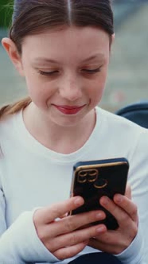 Teen Girl Enjoys Smartphone on City Street Closeup