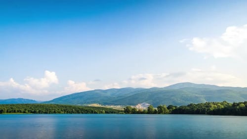 Lake with Clear Water and Stone Shore in Spruce Forest with Fir Trees Against a Daytime Sky