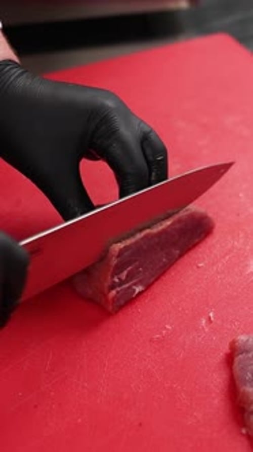 The chef prepares a dish of meat in the kitchen. Close-up