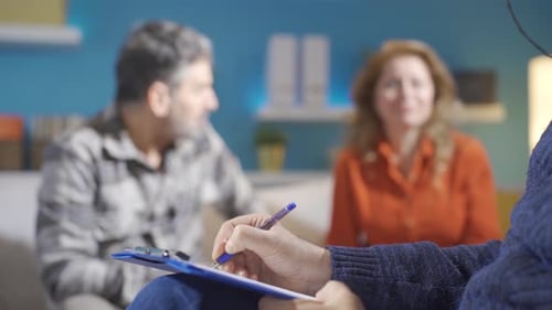 Psychiatrist taking notes while married couple discussing. Family problems.