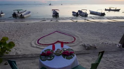 Romantic sunset dinner on beach. Table honeymoon set for two with glasses of champagne in restaurant