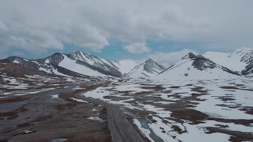 The Road Among Snowy Mountains And A Passing Car